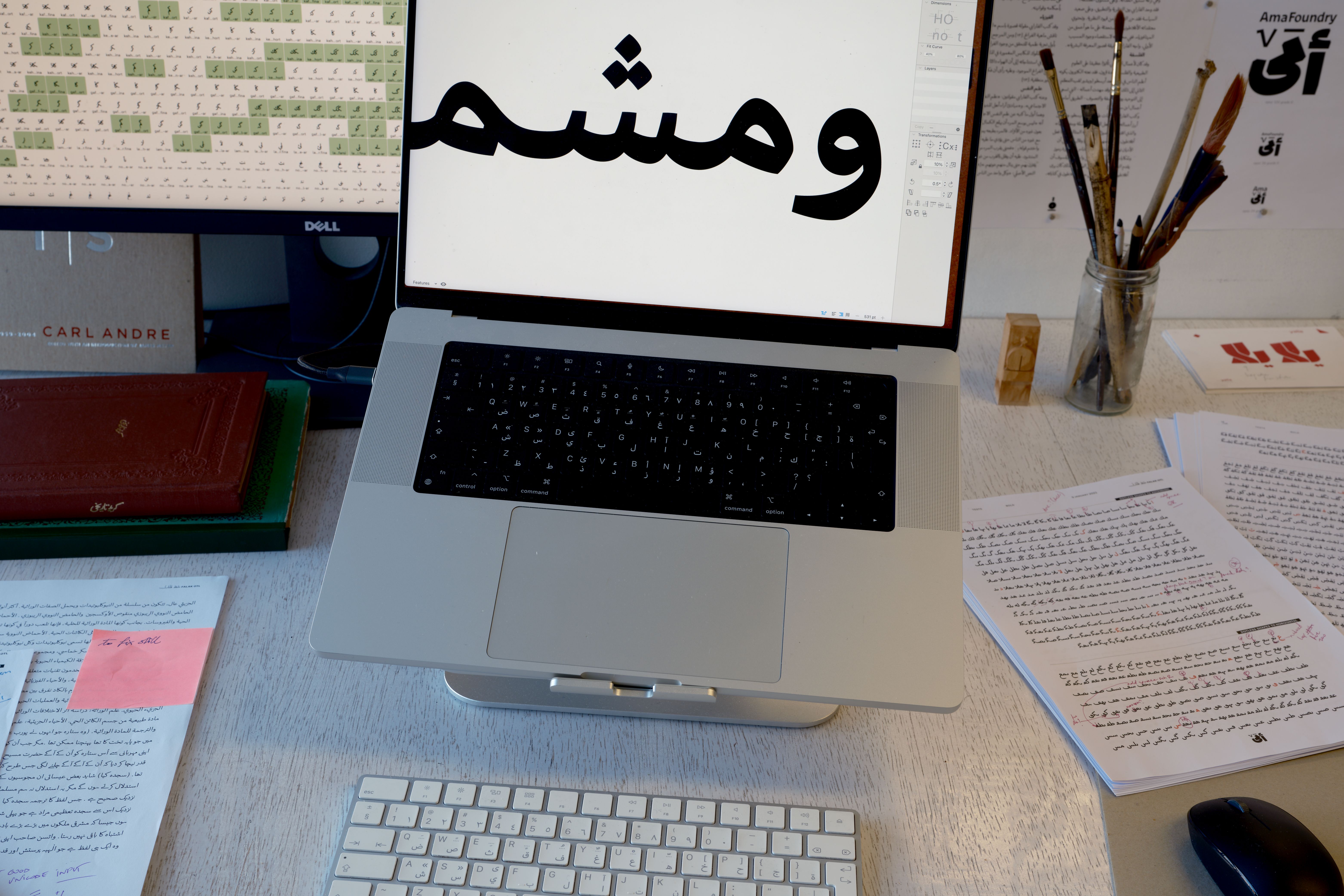 Arabic typography workspace with materials and printouts
